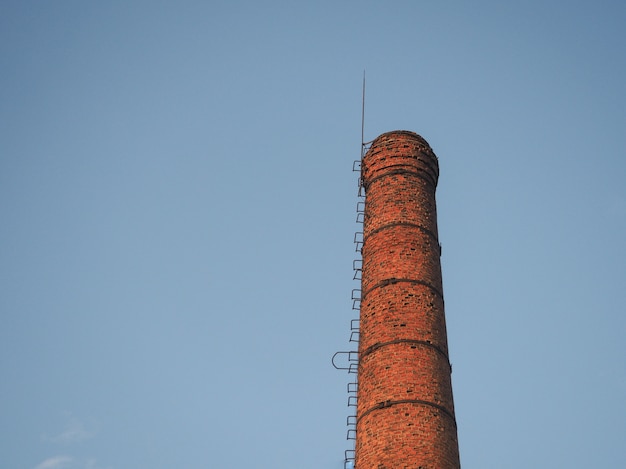 Tubulação industrial de vermelho de tijolo em um fundo do céu azul.