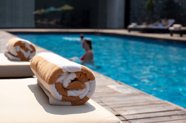 Tuch auf sunbed mit Frau im Swimmingpool auf Sommerferien.