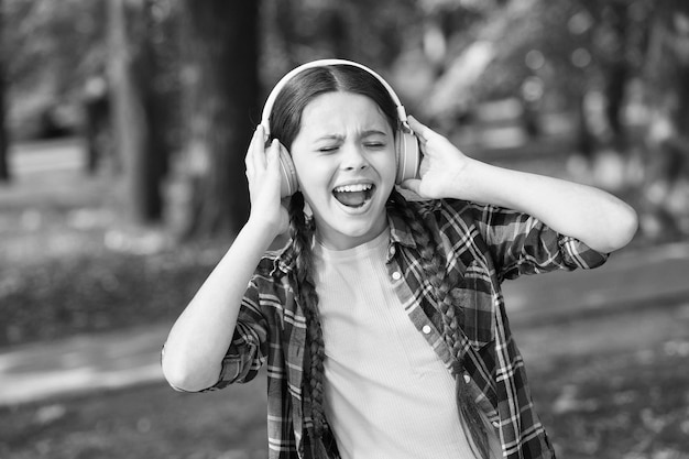 Tudo menos música Garota feliz canta música verão ao ar livre Criança pequena usa fones de ouvido tocando música Vida moderna Nova tecnologia Férias de verão Lazer e prazer Ceder ao ritmo