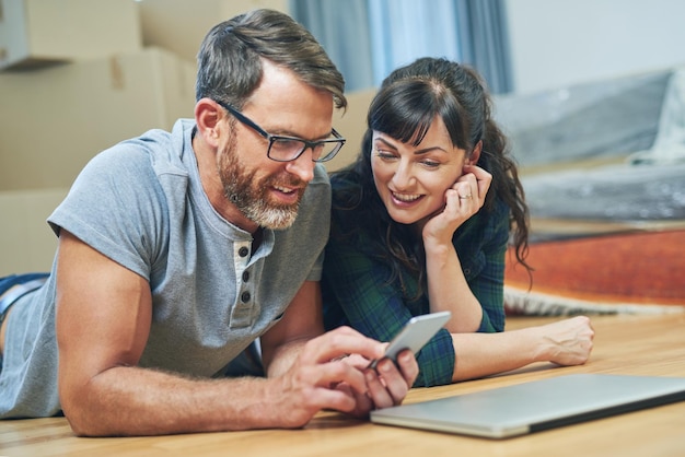 Tudo preparado e planejado para o dia da mudança com aplicativos móveis foto de marido e mulher usando um celular juntos no dia da mudança