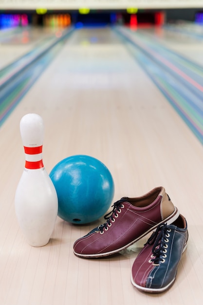 Tudo que você precisa para jogar boliche. close de tênis de boliche, bola azul e alfinete caídos na pista de boliche