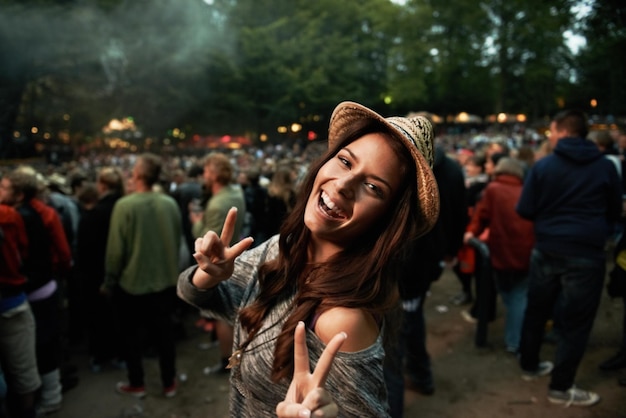 É tudo sobre a vibração Uma bela jovem mostrando um sinal de paz em um festival de música ao ar livre