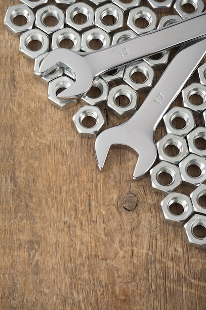 Foto tuercas de metal y herramienta de llave en la textura de la pared de madera