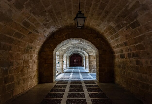 Foto türen und bögen im steinmuster der ehemaligen gefängnisburg mit altem licht, geschmiedete türen dunkler korridor