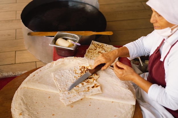 Türkin macht Tortillas auf einem rustikalen Holztisch