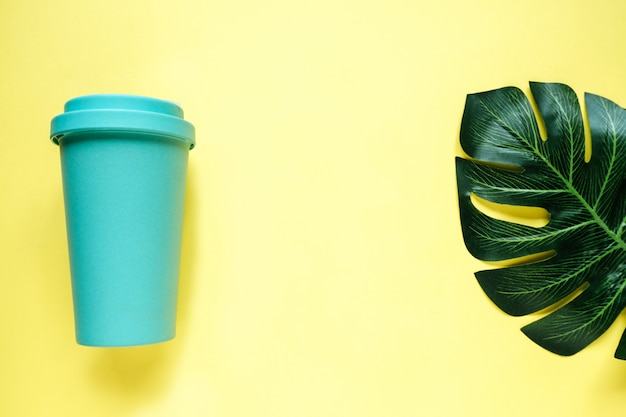 Türkis Bambus Kaffeetasse und Monstera Blatt auf gelbem Tisch