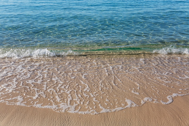 Türkis schaumige Welle an einem goldenen Sandufer