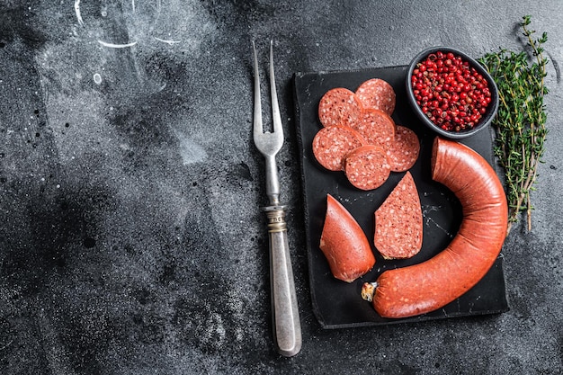 Türkische geschnittene Sucuk Fleischwurst auf einem Marmorbrett mit Thymian. Schwarzer Hintergrund. Ansicht von oben. Platz kopieren.