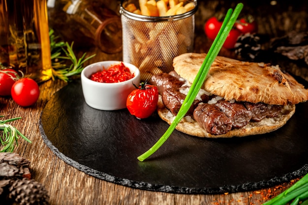 Türkische, orientalische Küche. Türkische Tortilla, Brötchen, Fladenbrot mit Kebab und eingelegten Zwiebeln. Servieren in einem Restaurant auf einer schwarzen Tafel auf einem Holztisch