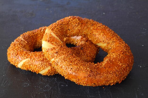 Türkischer Simit-Bagel mit Sesamkörnern auf schwarzem Hintergrund bestäubt