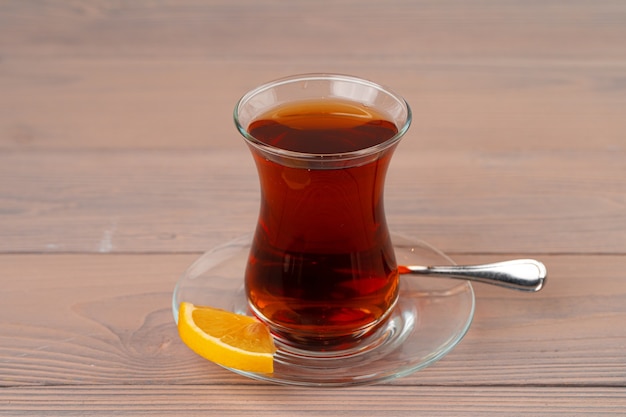 Türkischer Tee in der Glasschale mit Zitronenstück auf Holztisch