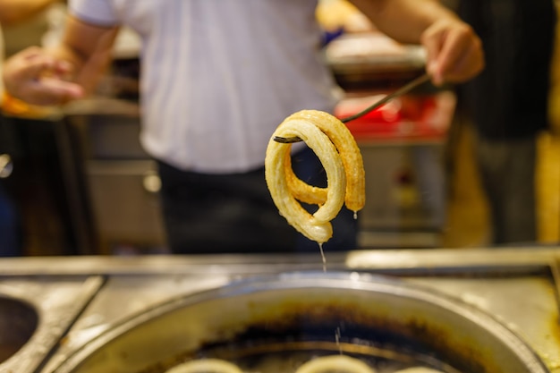 Türkisches Dessert Churros Halka Tatli, das in heißem Öl gebraten wird Türkische Donuts oder traditionelle Ringsüße Ha