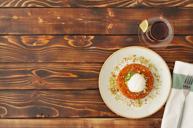 Türkisches Dessert kunefe mit Eiskugel auf Holzoberfläche