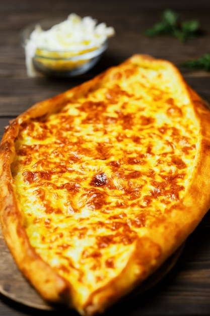 Türkisches Fladenbrot (Pide) mit Käse. Kasarli pide auf dem dunklen Holztisch. Nahansicht. Traditionelle türkische Pizza