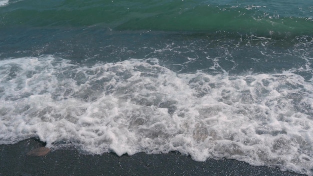 Türkisfarbene Meereswellen brechen an der felsigen Küste und bilden Schaum Ein Video von dunkelblauem Meerwasser und Schaumwellen Video in Zeitlupe