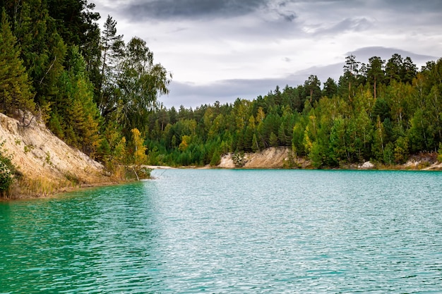 Türkisfarbener See in einem Nadelwald im Herbst