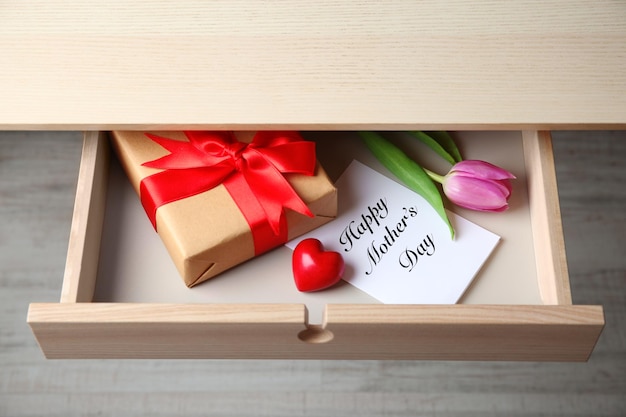 Tulipa rosa de presente e cartão de felicitações para o dia das mães na gaveta de madeira