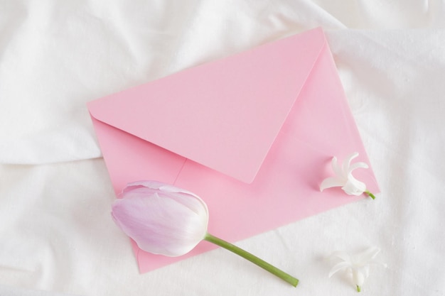 Tulipa rosa e pequena flor de jacinto branco e envelope rosa na flor de cartão-presente de roupa de cama branca para qualquer um