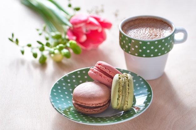 Tulipa rosa, frésia, café expresso e macarons na frente, flores da primavera nas costas