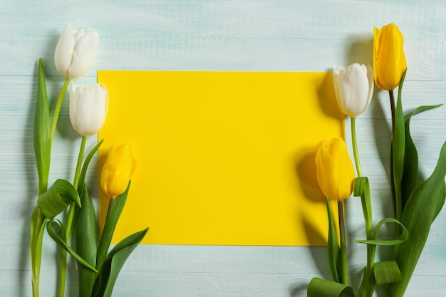 Tulipanes amarillos y blancos sobre un fondo de madera clara