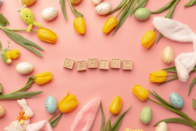 Tulipanes amarillos y decoración de Pascua sobre un fondo rosa Letras de madera Centrado en Pascua Vista superior