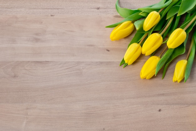 Tulipanes amarillos en el espacio de fondo de madera para texto