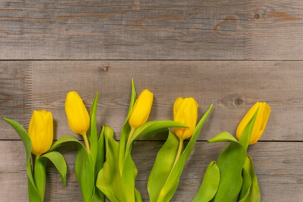 Foto tulipanes amarillos en la mesa de madera rústica. vista superior con espacio de copia.