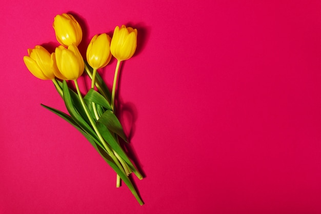 Tulipanes amarillos sobre una mesa roja