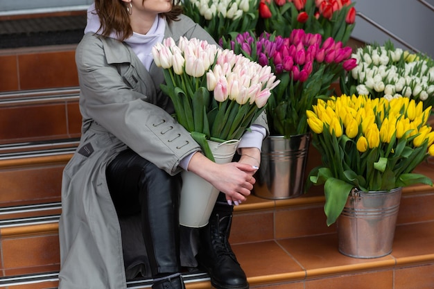 Tulipanes de color rosa en mano de mujer Mujer hermosa joven sosteniendo un ramo de primavera sobre fondo de flores Ramo de flores de primavera frescas cortadas en manos femeninas Concepto de tienda de flores