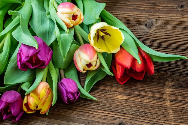 Tulipanes coloridos en la mesa de madera