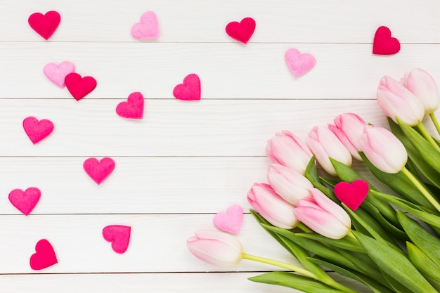 Tulipanes y corazón rosados en el fondo de madera blanco. Fondo del día de San Valentín.