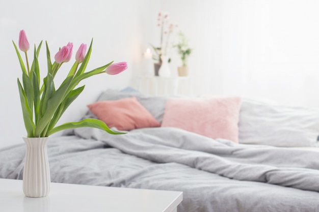 Tulipanes en florero en dormitorio acogedor