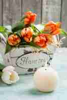 Foto tulipanes naranjas en cesta de madera y cadle iluminado