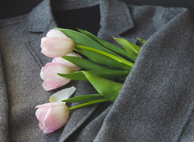 Tulipanes de primavera en chaqueta gris de mujer