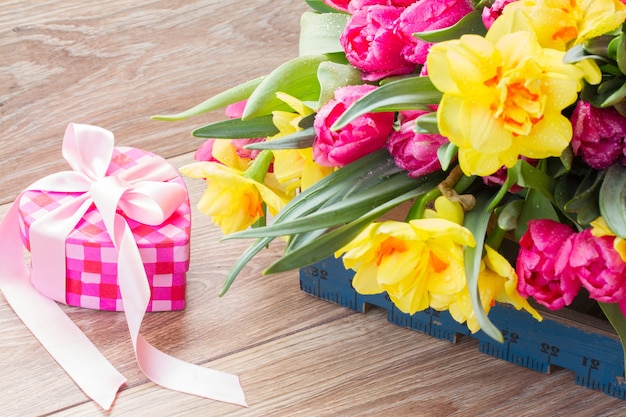 Tulipanes de primavera y flores de narciso con caja de regalo rosa