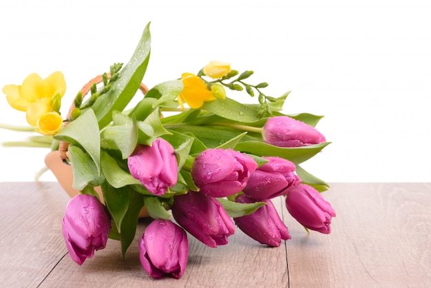 Tulipanes de primavera y fresia en una cesta