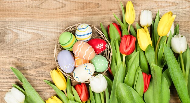 Tulipanes de primavera y huevos de pascua en un plato sobre una mesa de madera