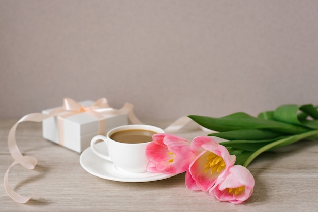 Tulipanes de primavera rosa, una caja de regalo y una taza de café. El concepto de día de la mujer o día de la madre. Festival de Primavera