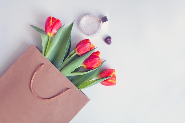 Tulipanes rojos en bolsa de papel con perfume Tarjeta de flores con hermoso ramo de regalo con espacio de copia