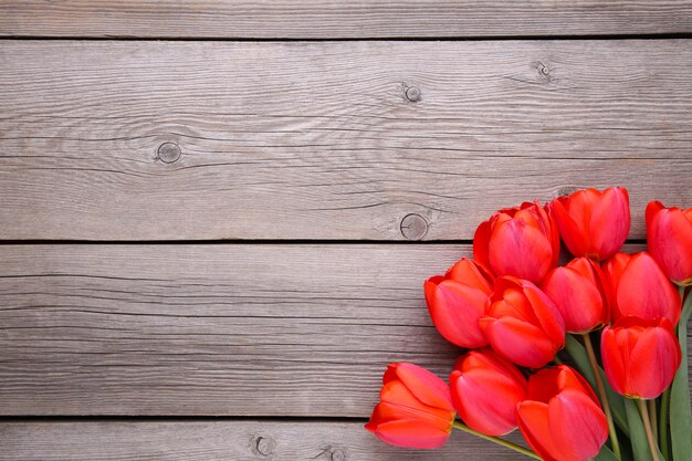 Tulipanes rojos en un gris de madera.