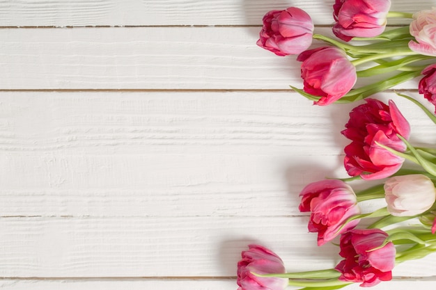 Tulipanes rojos en mesa de madera blanca