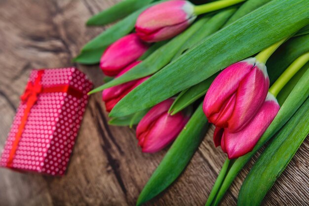 Tulipanes rojos y regalo en una mesa de madera