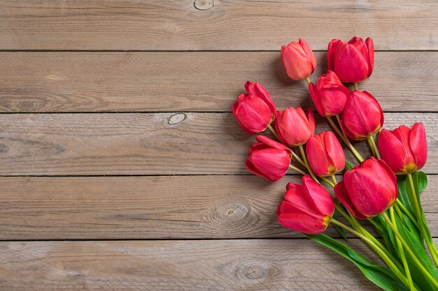 Tulipanes rojos sobre fondo de madera con espacio para texto, mensaje.