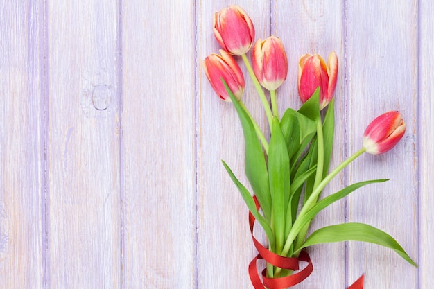 Tulipanes rojos sobre mesa de madera violeta