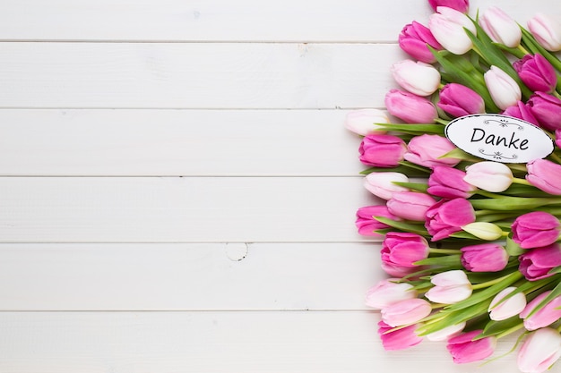 Tulipanes rosa sobre mesa de madera blanca