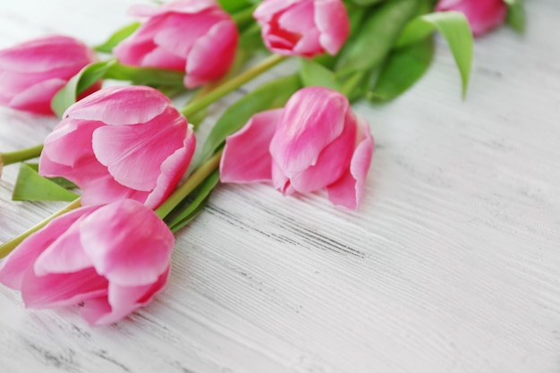 Tulipanes rosados frescos en una mesa de madera de cerca