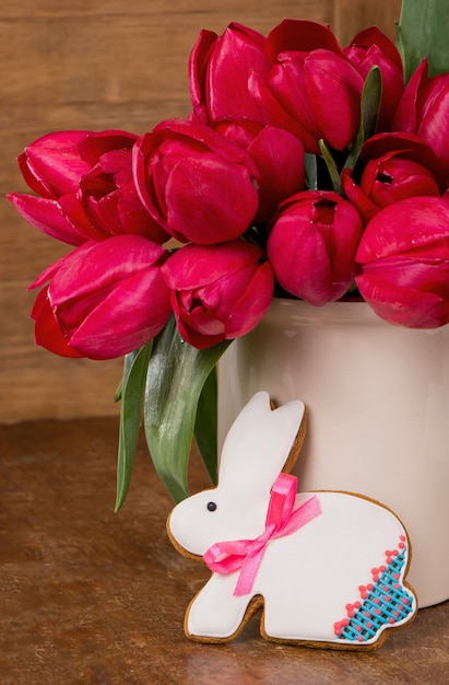 Tulipanes rosados y galleta de conejito de Pascua en superficie de madera. Concepto de primavera o pascua