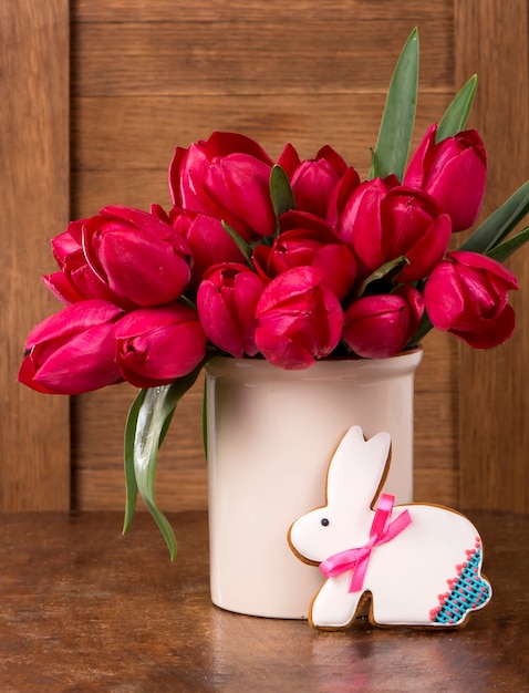 Tulipanes rosados y galleta de conejito de Pascua en superficie de madera. Concepto de primavera o pascua