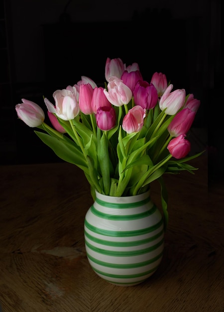Tulipanes rosados en un jarrón de cerámica aislado sobre un fondo negro en un estudio con espacio para copiar Planta de maceta de flores florecientes vibrantes que simbolizan el amor Dulce gesto para el día de San Valentín