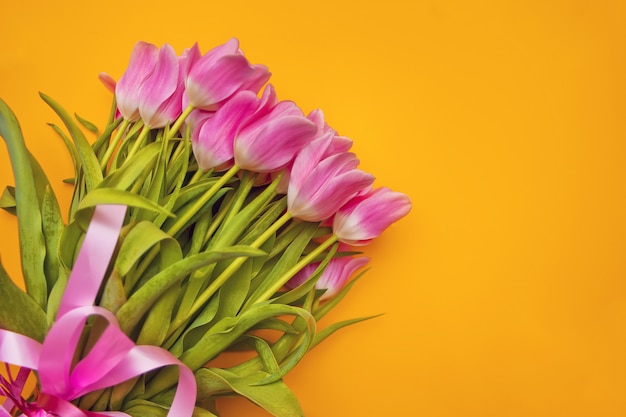 Foto tulipanes rosados en la superficie amarilla. copia espacio